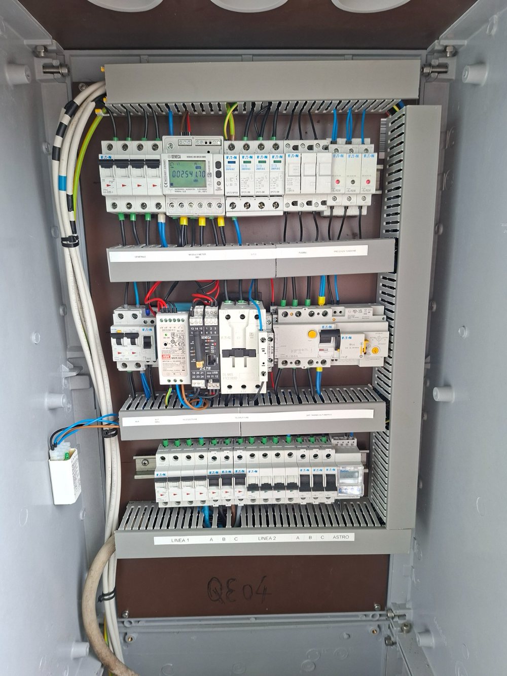 The inside of a street lighting cabinet: breakers, a MID energy meter, surge protection, contactors and the control module on the DIN rails