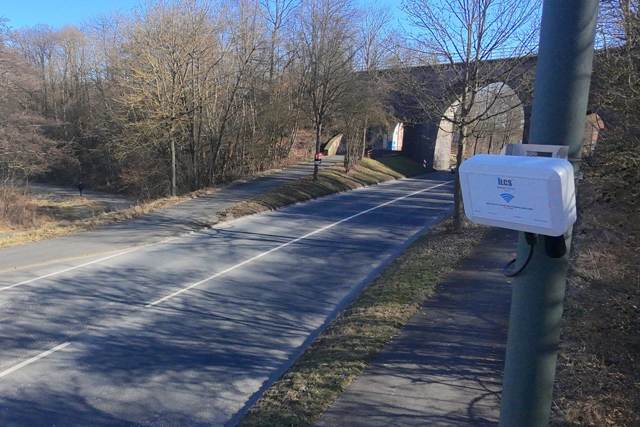 An air quality, noise and traffic node mounted on a pole beside a road