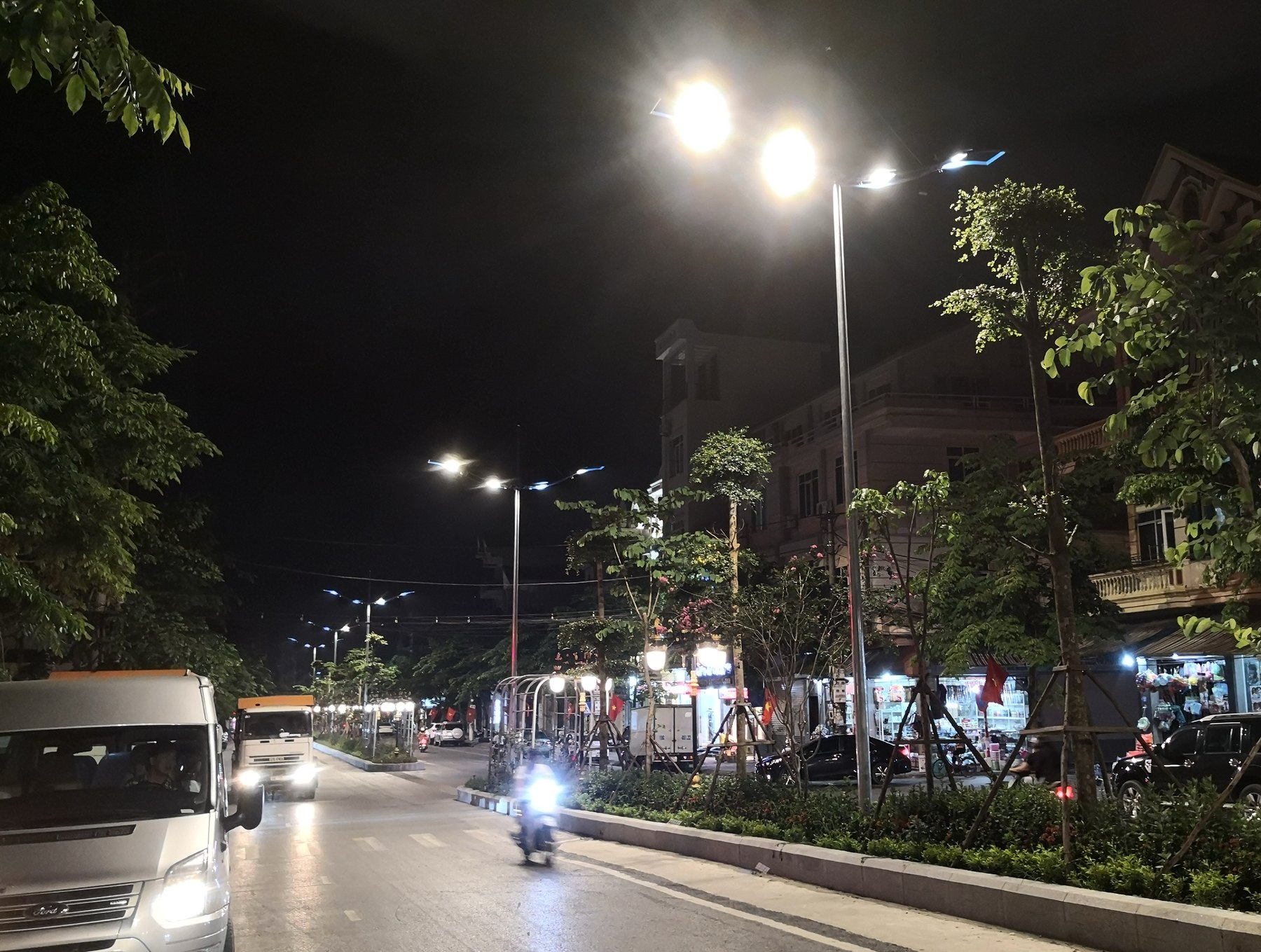 A lit street at night with the devices of the network on the poles